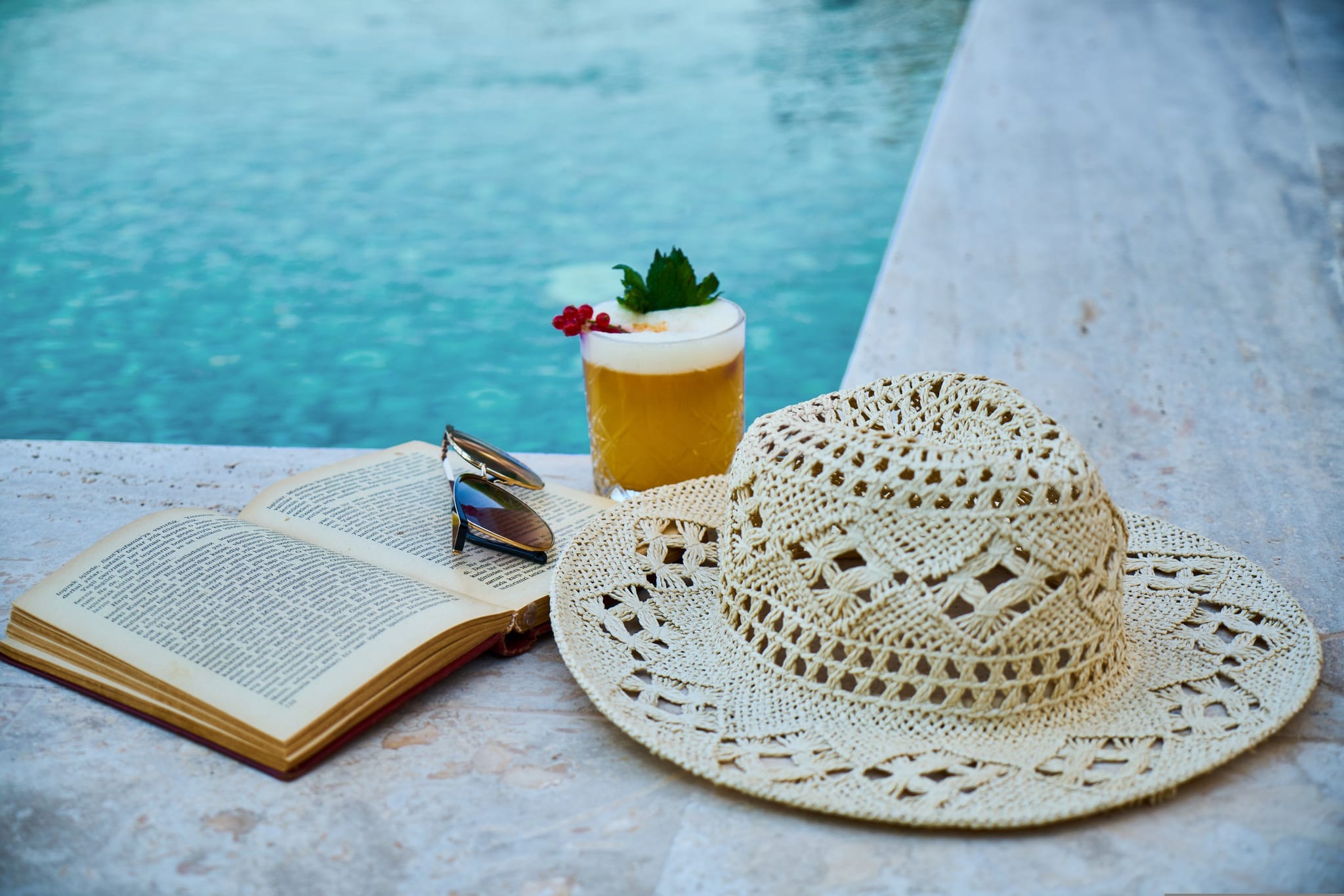 Livre, lunettes, chapeau et cocktail au bord piscine, Hôtel près de Sarlat avec Piscine, Maison Borrèze.